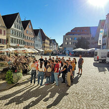 Studienanfänger stehen bei einer Stadtführung auf dem Marktplatz.