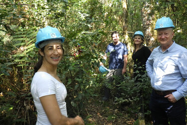 Teilnehmer stehen im Wald mit blauen Helmen auf dem Kopf und schauen in die Kamera.