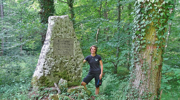 Jana Schumacher steht im Wald neben einem Kleindenkmal