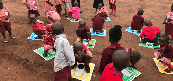 Kinder in Uganda sitzen im Kreis auf dem Boden.