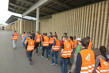 Studierende laufen in Warnwesten über das Betriebsgelände