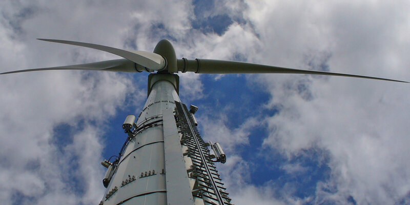 Windrad von unten am Mast entlang nach oben fotografiert - teilweise bewölkter Himmel