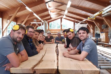 Gruppenfoto mit Studierenden im Sägewerk an einem Tisch
