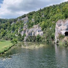 Blick über die Donau hinweg auf einen Straßentunnel im Felsen