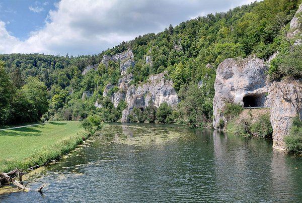Blick über die Donau hinweg auf einen Straßentunnel im Felsen