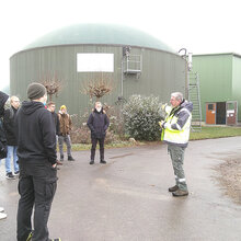 Studierende und Referent vor einer Biogasanlage