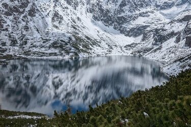 See, umgeben von schneebedeckten Bergen und Wäldern