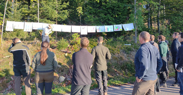 Studierende lauschen dem Referenten im Wald