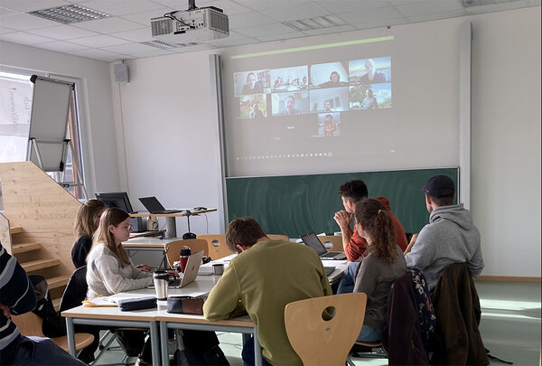 Studierende sitzen zusammen an einem Tisch und machen Gruppenarbeit