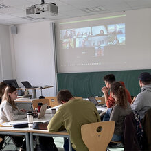 Studierende sitzen zusammen an einem Tisch und machen Gruppenarbeit