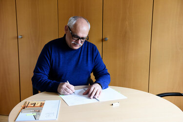 Rektor Prof. Bastian Kaiser unterzeichnet am Tisch den Vertrag