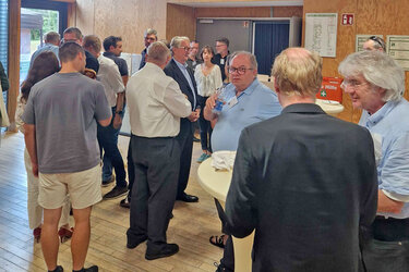 Besucher tauschen sich an Stehtischen bei Essen und Trinken untereinander aus