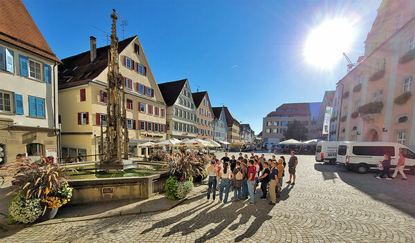 Studienanfänger stehen bei einer Stadtführung auf dem Marktplatz.