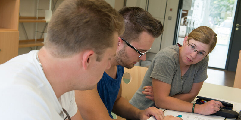 Drei Studierende lernen gemeinsamen an einem Tisch in der Bibliothek der Hochschule Rottenburg