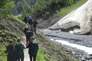 Studierende wandern im an einem Gebirgsbach entlang