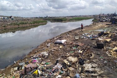 Weitläufige Mülldeponie direkt an einem verschmutzten Wasserlauf