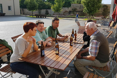 Teilnehmer unterhalten sich bei einem Bier am Tisch