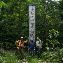 Gruppenfoto im Wald vor einer Holzsäule mit Schriftzeichen