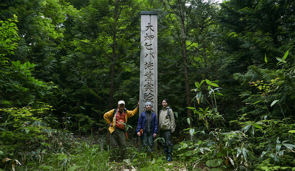 Gruppenfoto im Wald vor einer Holzsäule mit Schriftzeichen