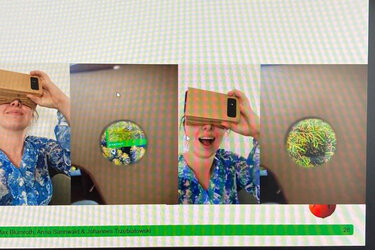 Screenshot einer Video-Konferenz. Zusehen sind die Teilnehmer und auf der Präsentation eine Studentin mit einer Virtual Reality Brille aus Karton. 