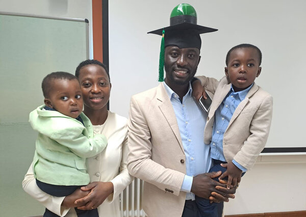 Gruppenfoto: Joseph Kusi mit Familie und Doktorhut (inkl. Modell einer Biogasanlage) nach erfolgreicher Verteidigung