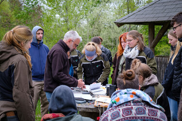 Studierende stehen im Arboretum um einen Tisch mit vielen Büchern und Geräten darauf
