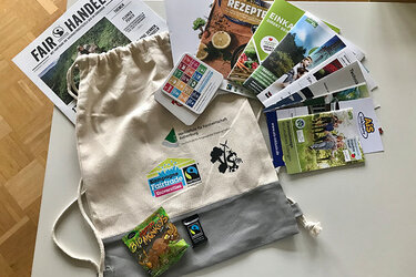Erstsemesterbegrüßungstüte: der Inhalt des Beutels liegt zu Präsentationszwecken daneben und darauf. Zeitschriften und Flyer zum Thema Nachhaltigkeit, Fairtrade-Süßigkeiten.