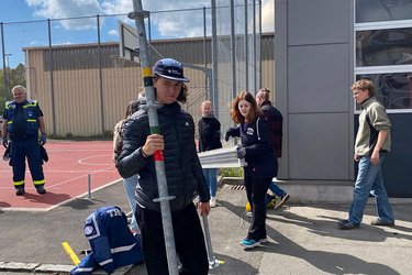 Student mit einer Stange auf einem Sportgelände