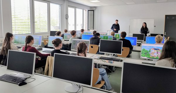 Schülerinnen und Schüler sitzen jeweils an einem PC in einem Computerraum der Hochschule und folgen den Anweisungen des Dozenten.