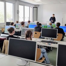 Schülerinnen und Schüler sitzen jeweils an einem PC in einem Computerraum der Hochschule und folgen den Anweisungen des Dozenten.