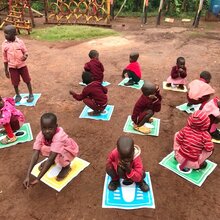 Kinder in Uganda sitzen im Kreis auf dem Boden.
