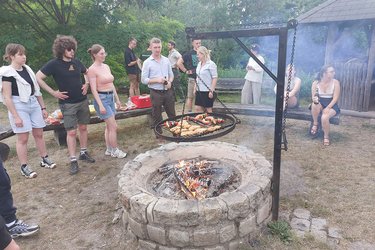 Teilnehmer stehen an der Feuerstelle und grillen