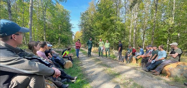 Studierende im Wald lauschen den Referenten