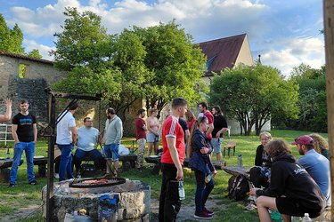 Die ehemaligen Studierenden stehen bei sonnigen Wetter im Arboretum und unterhalten sich.