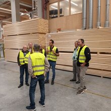 Teilnehmer stehen mit gelben Warnwesten in einem Sägewerk
