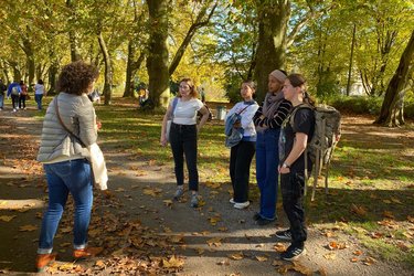 Austauschstudierende stehen auf der Platanenallee in Tübingen und hören der Stadtführerin zu