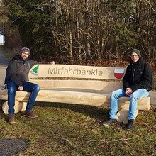 Zwei Studierende sitzen auf dem Mitfahrbänkle