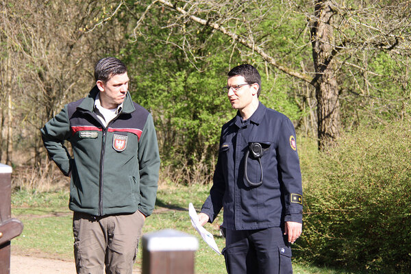 Ein Förster und ein Feuerwehrmann unterhalten sich im Wald