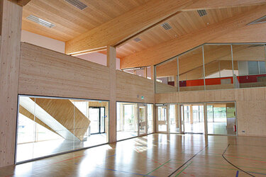 Blick in eine Sporthalle in Holzbauweise und viel Glas