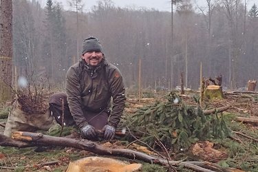 Ein Student lächelt beim Pflanzen in die Kamera