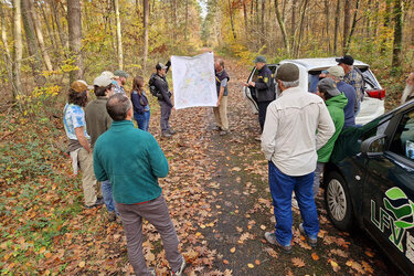 Die Teilnehmer im Wald. Anhand einer Karte wird der Standort erläutert.