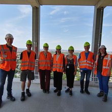 Gruppenfoto der Teilnehmer auf der Bausstelle mit orangenen Warnwesten und Helmen