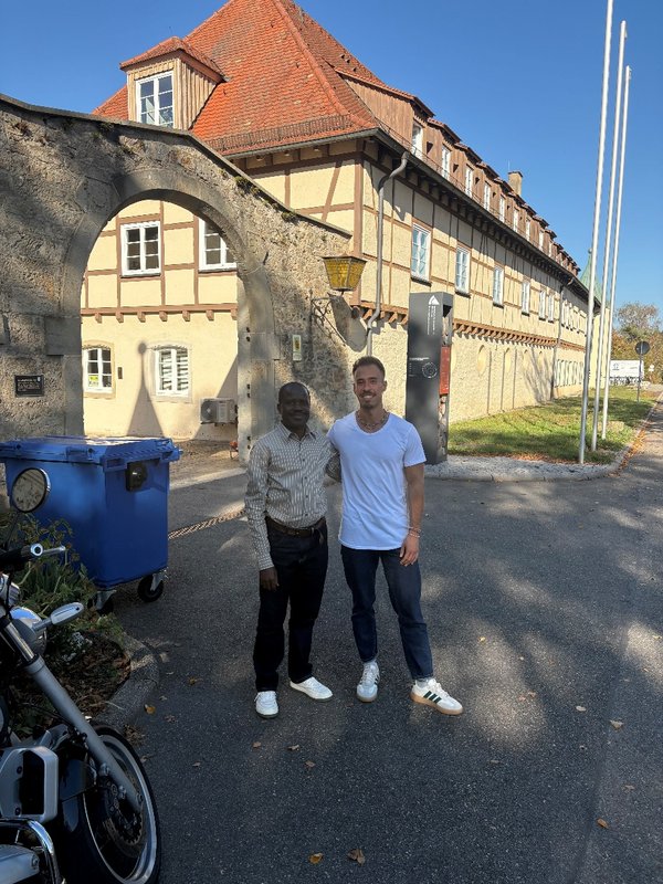 Gemeinsamen Foto vor dem Hochschulgebäude: Gilbert Nsabimana (links) zusammen mit Jannis Bahnmüller (rechts) beim Besuch der Partnerorganisation COCOCA an der HFR