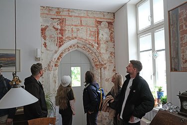 Studierende stehen in einer Gruppe und hören dem Referenten zu