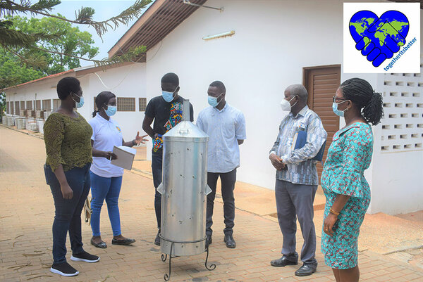 Mitglieder des Projekt-Teams im Gespräch mit Studenten der University of Ghana. Im Vordergrund ist ein Pyrolyseofen zu sehen.