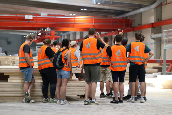 Studierende stehen mit orangenen Westen im Sägewerk