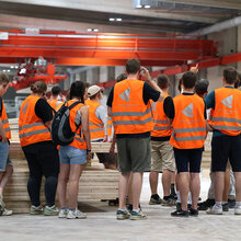 Studierende stehen mit orangenen Westen im Sägewerk
