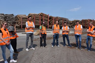 Studierende mit Warnwesten auf Holzlagerplatz