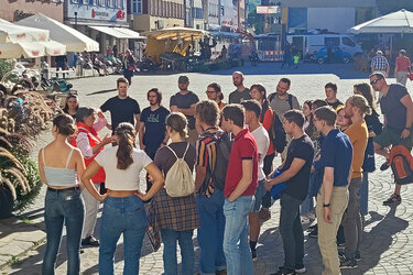 Studienanfänger stehen bei einer Stadtführung auf dem Marktplatz.