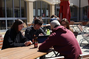 Studierende sitzen mit einem Notebook an einem Tisch und bearbeiten gemeinsam ein Thema